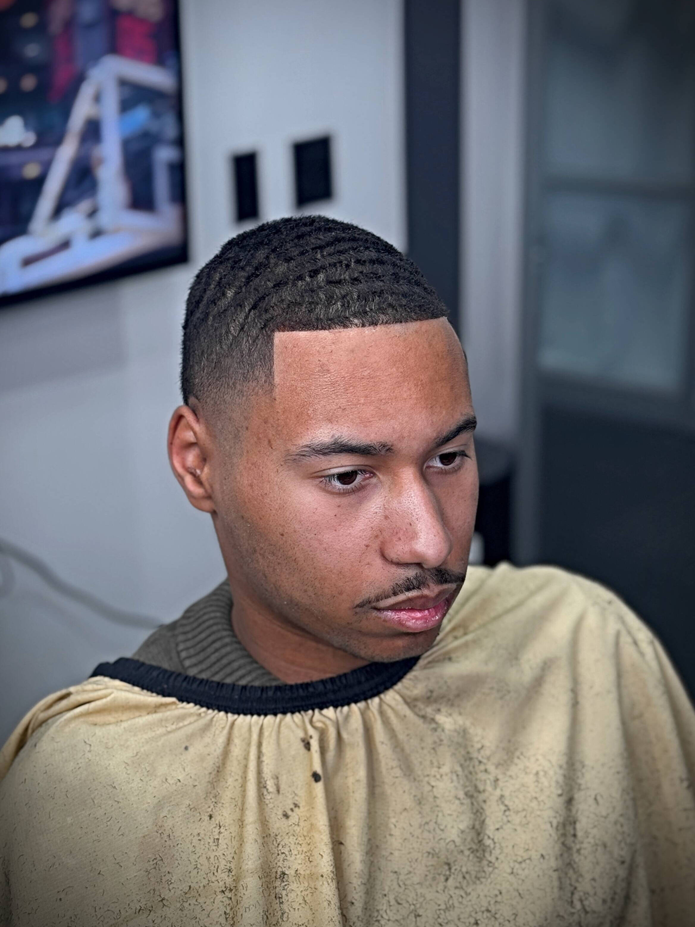 Fade haircut result on a client in the shop, with artwork on the wall behind